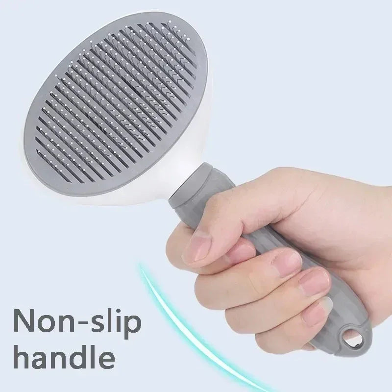 Hand holding a gray pet grooming brush with non-slip handle for dogs and cats.